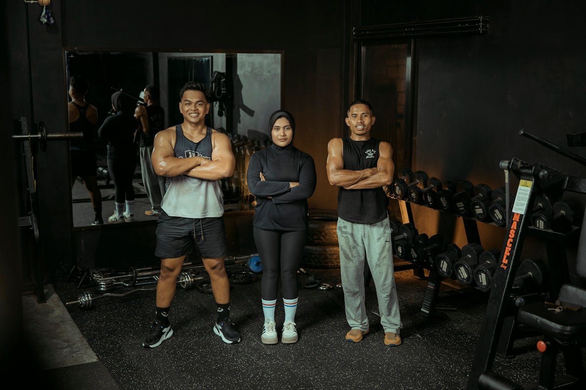 Three people pose at the gym.